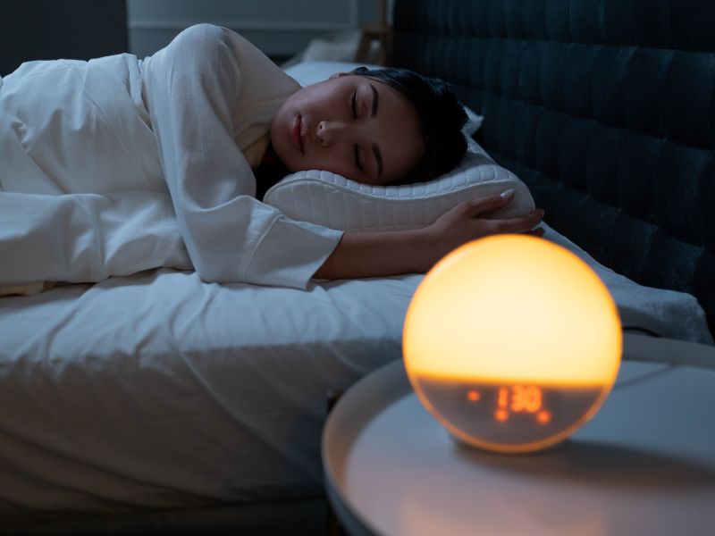 sleeping woman with sunrise alarm clock